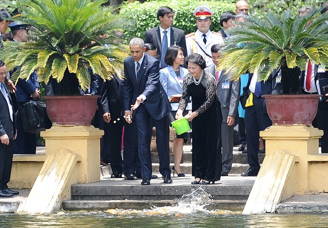 Ông Obama cho cá ăn trước sự chứng kiến của thành viên phái đoàn Mỹ và quan chức Việt Nam